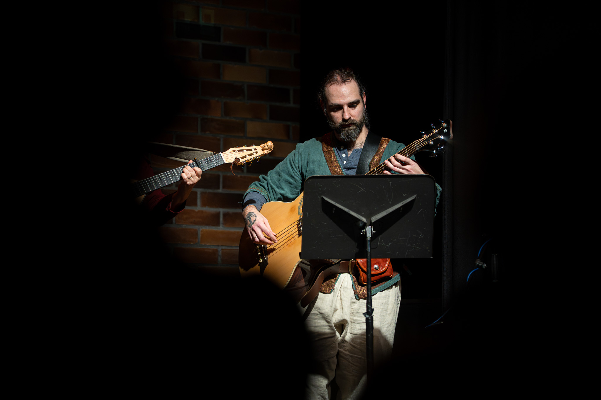 Musiker spielt ein akustisches Saiteninstrument hinter einem Notenständer
