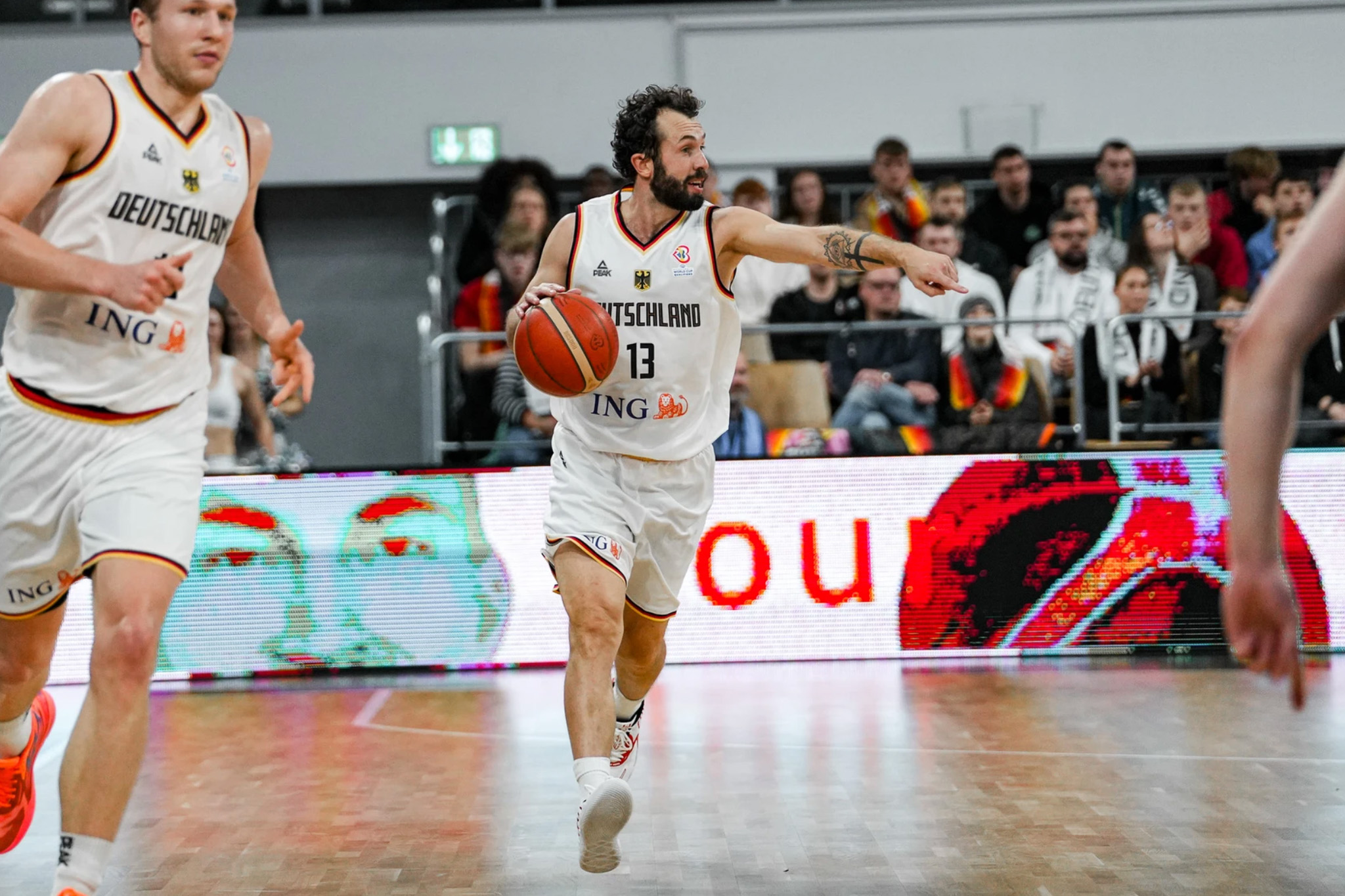 Ein deutscher Nationalspieler führt den Ball und weist auf eine Spielposition