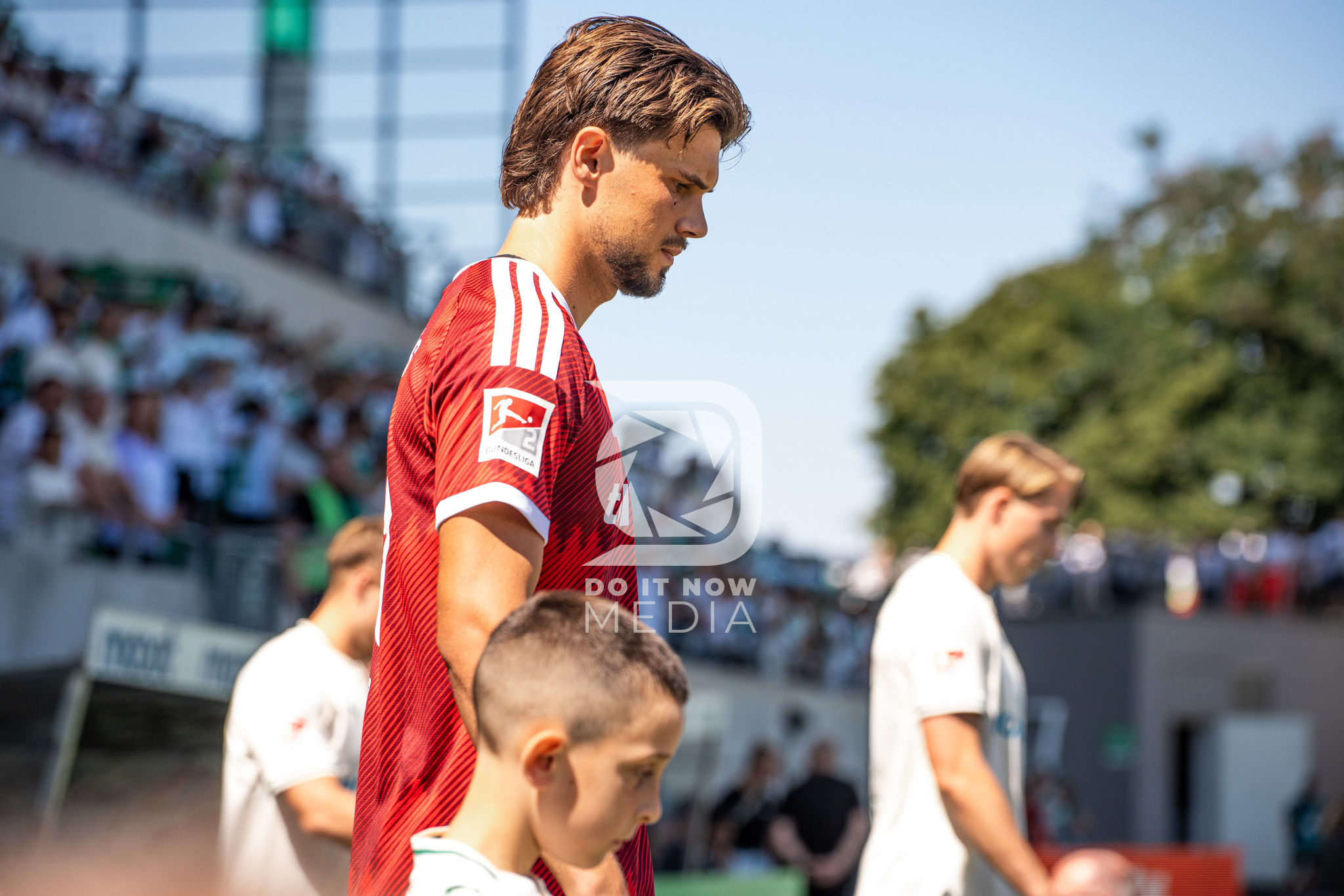 Ein FCN-Spieler läuft mit einem Einlaufkind auf den Rasen.