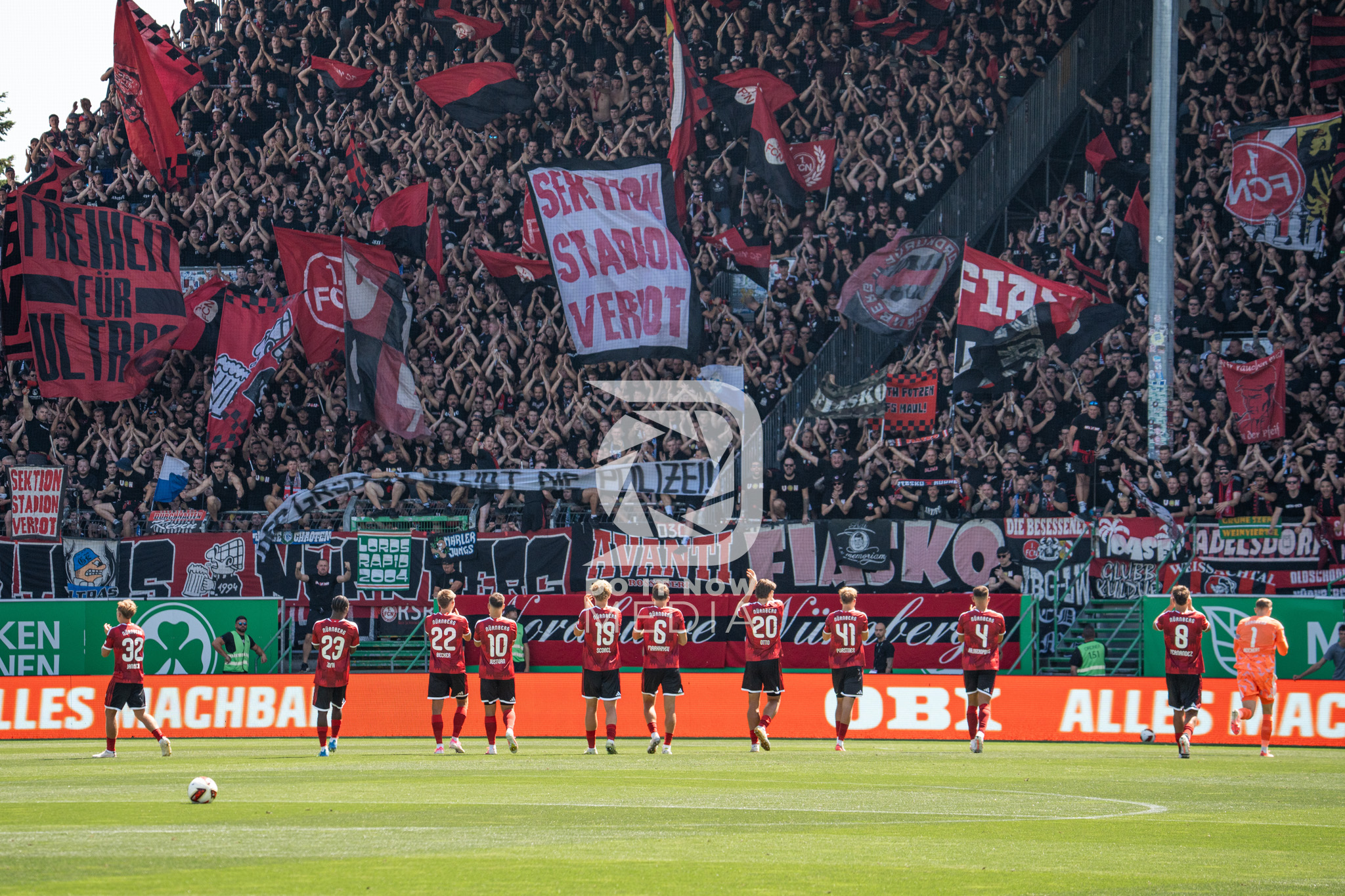 Die FCN-Mannschaft vor dem mit Fahnen geschmückten Gästeblock in Fürth.