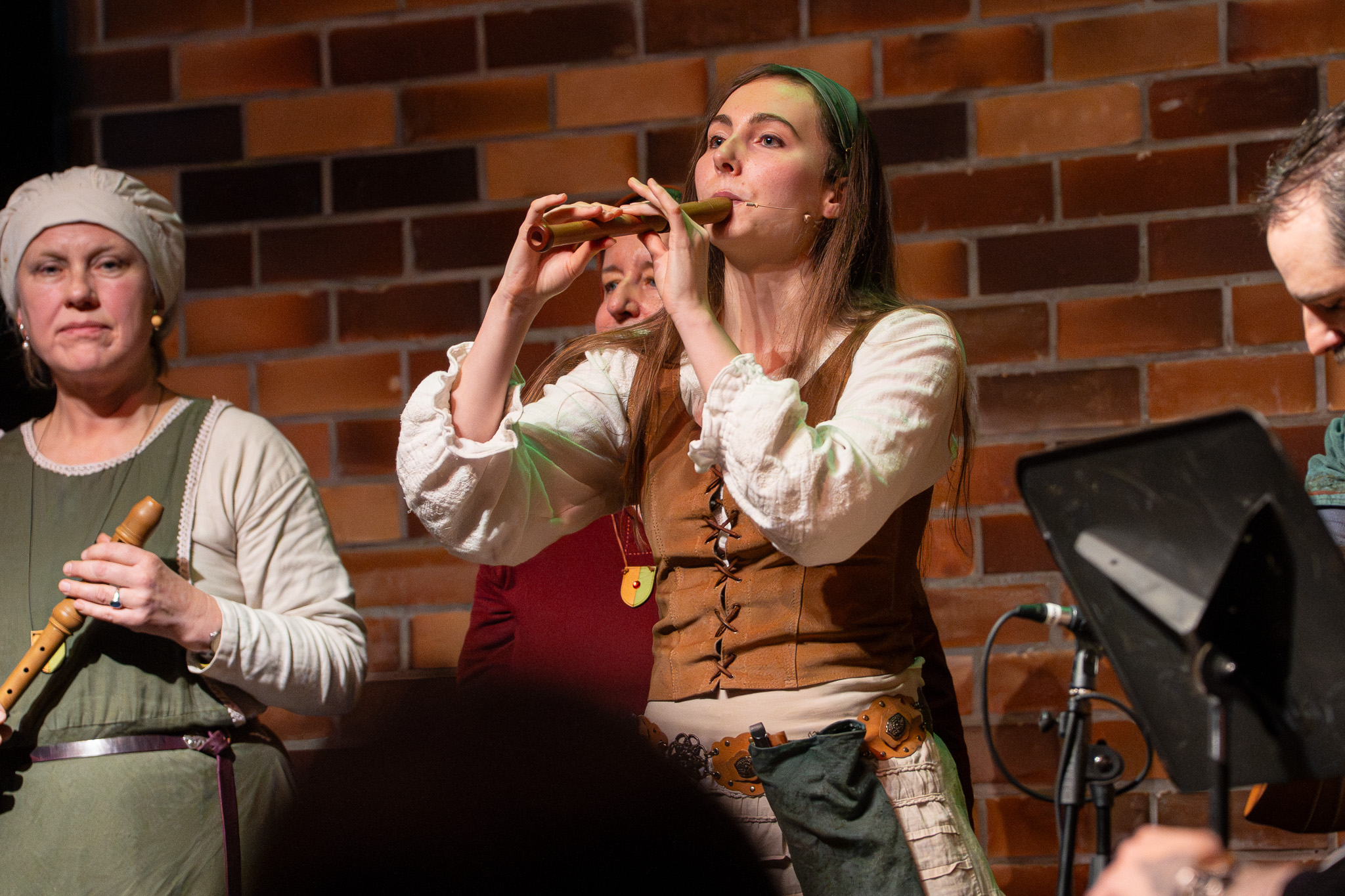Musikerin spielt Blockflöte vor der Backsteinwand