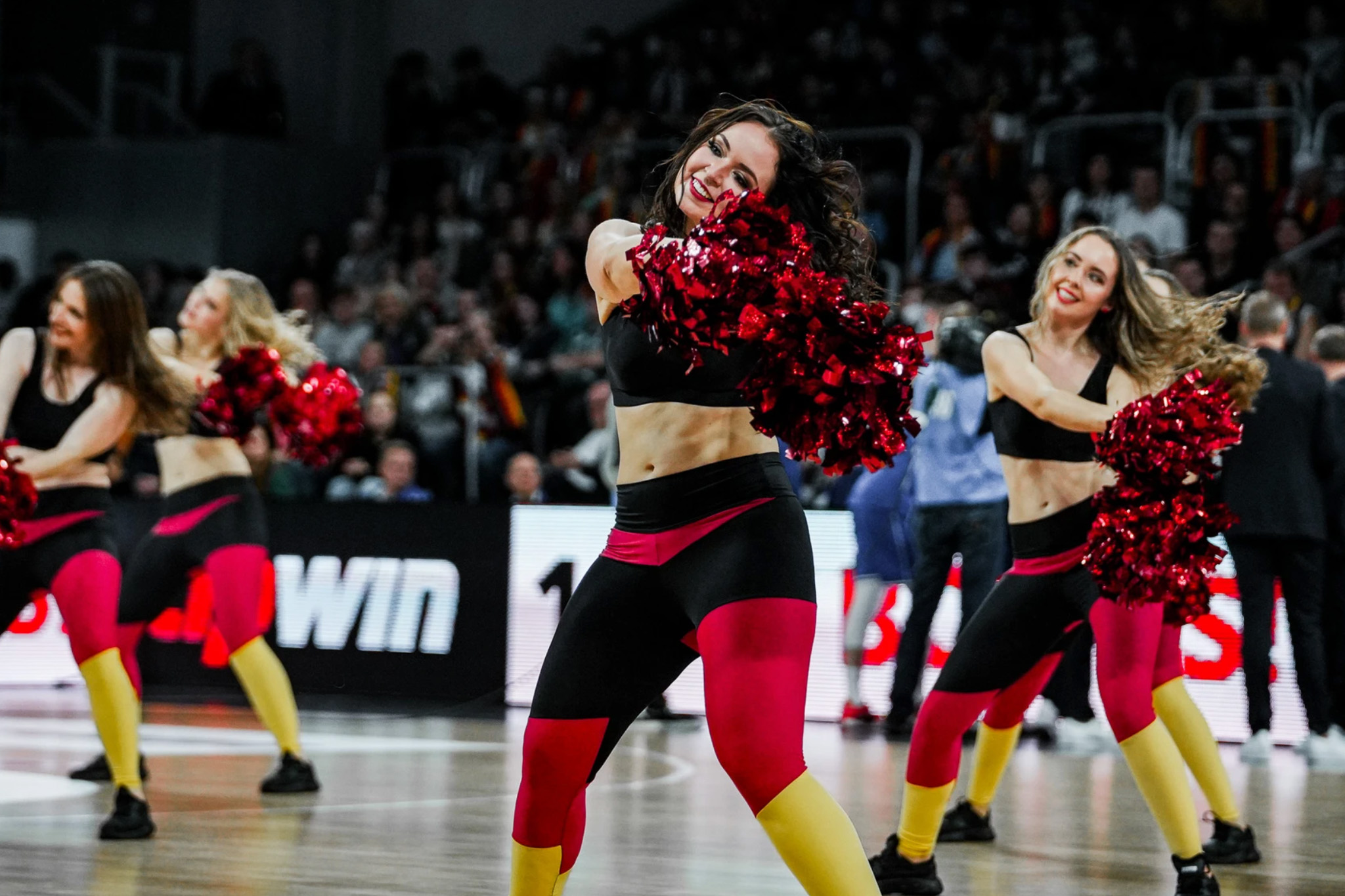 Cheerleader mit roten Pompons am Spielfeldrand