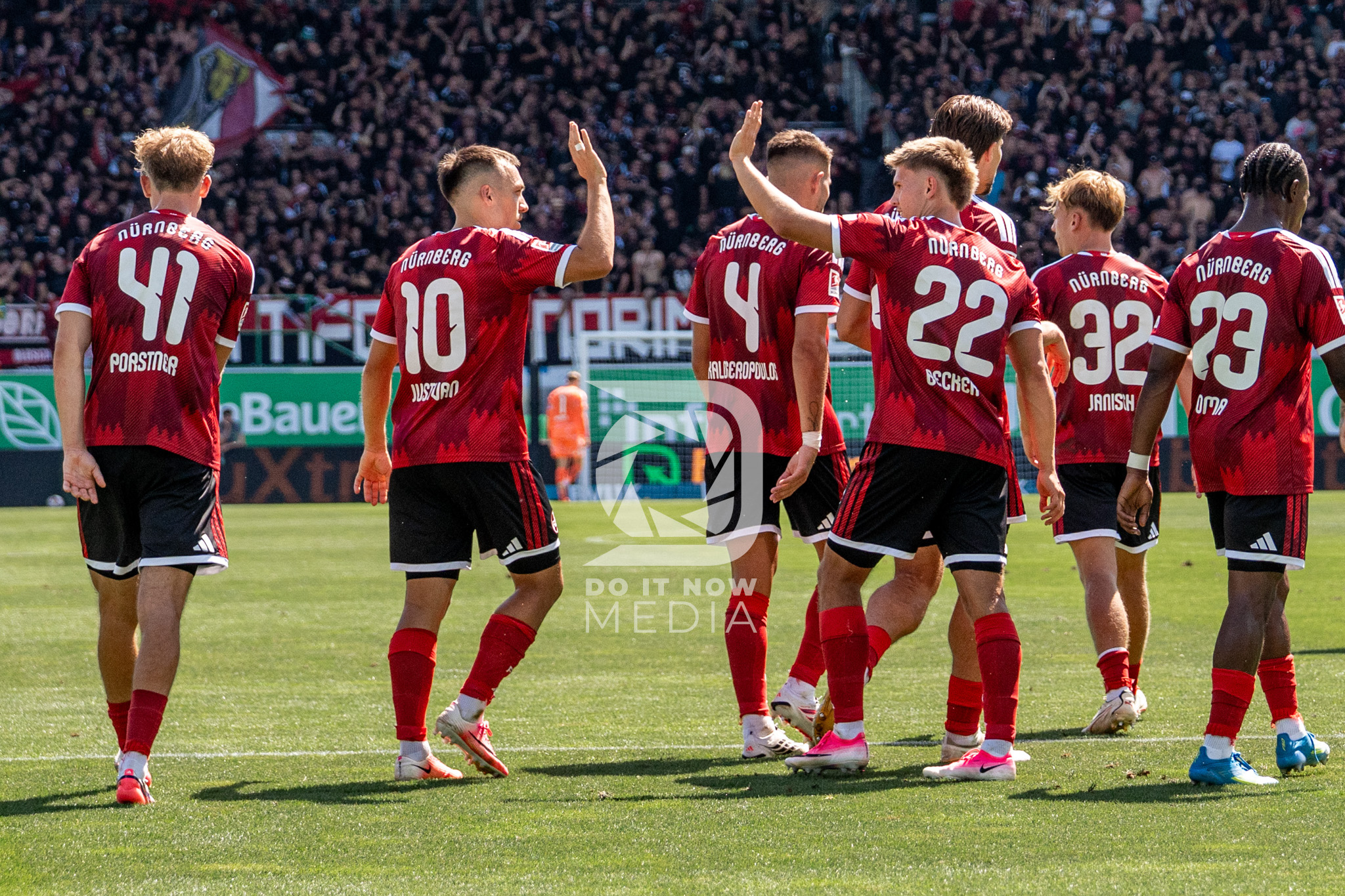 FCN-Spieler klatschen auf dem Rasen miteinander ab.